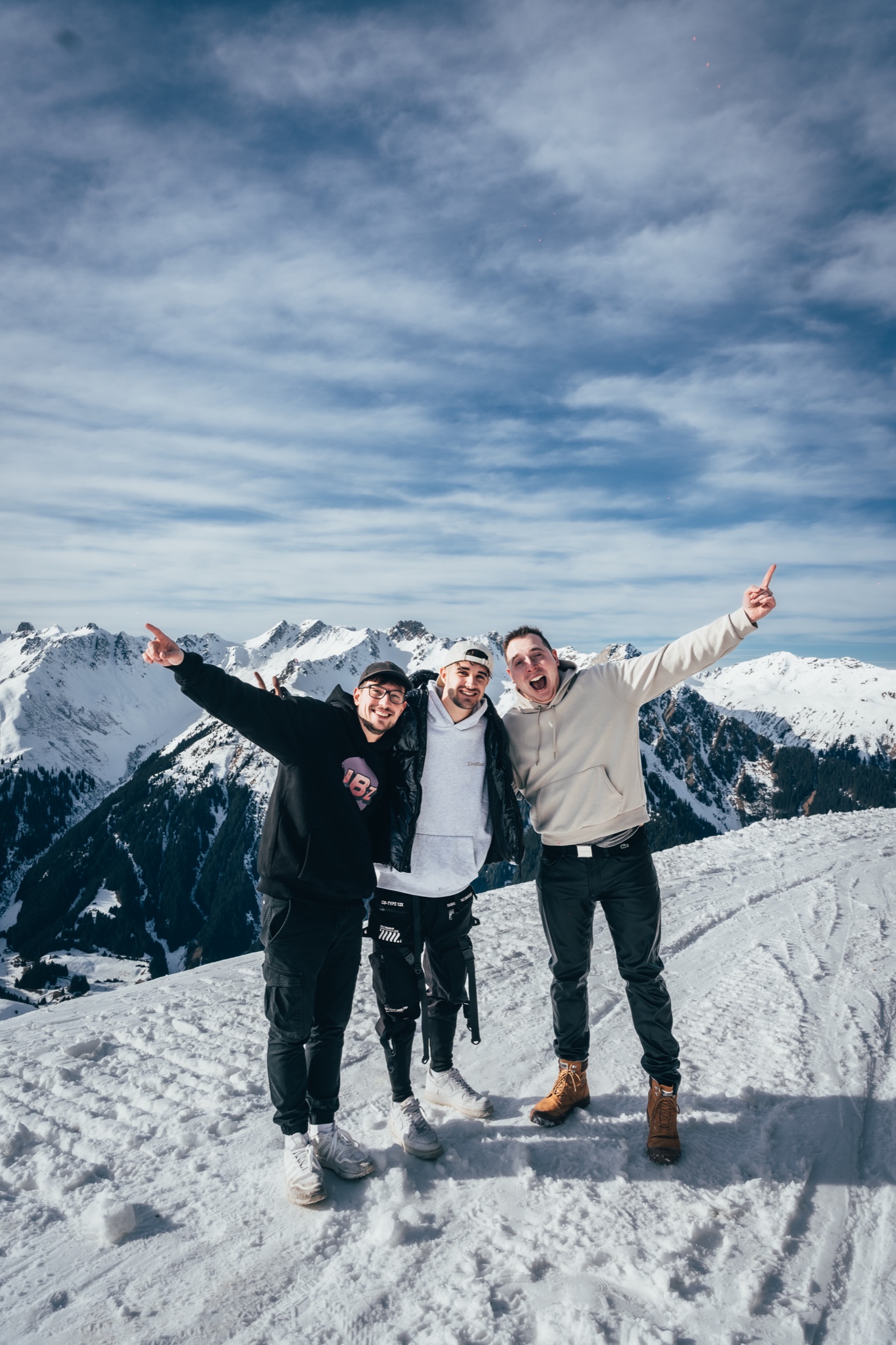 Drei Freunde mit erhobenen Händen auf dem Gipfel beim Mountain Beats Festival